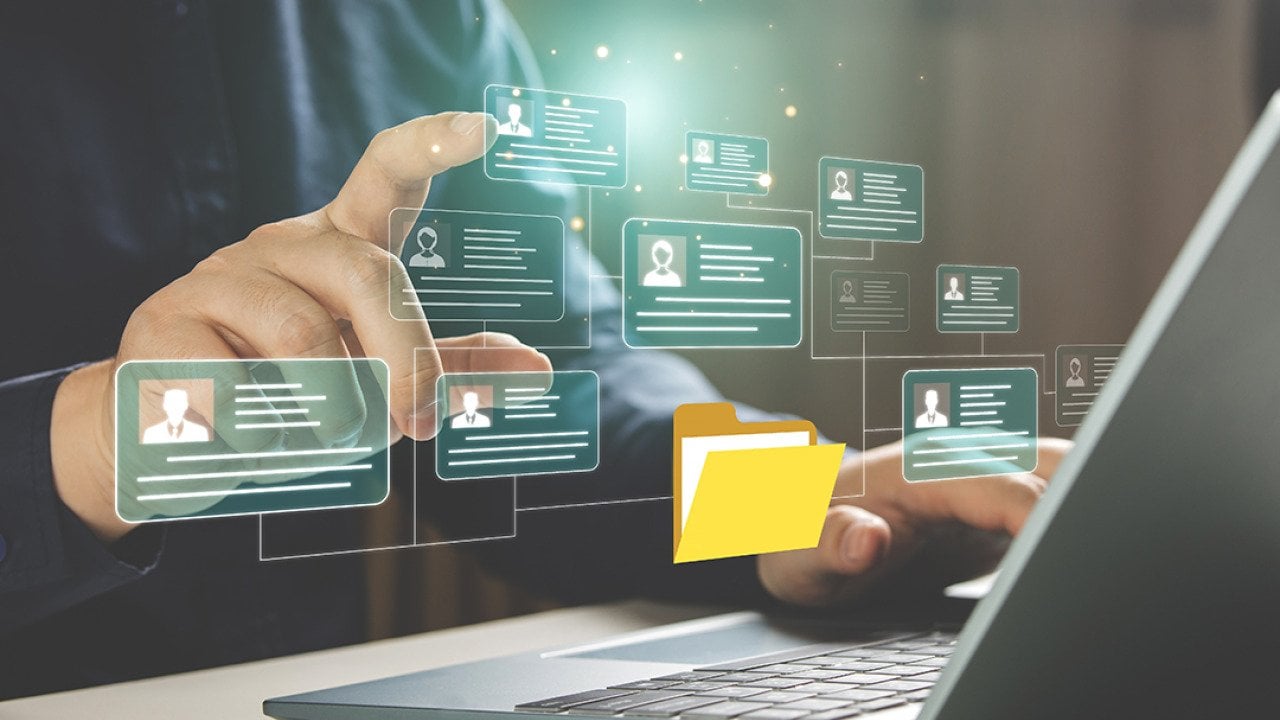 Businessperson using a laptop hovers at graphic illustration of a personal file management software.