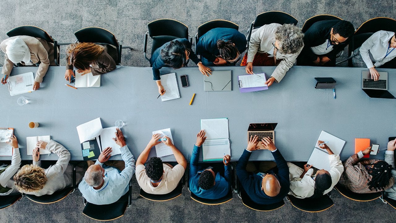 Top view of a large business group around a table during a meeting.