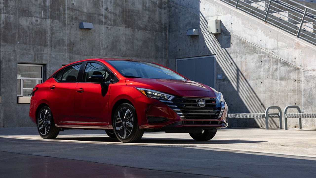 A red 2025 Nissan Versa parked in a concrete lot.