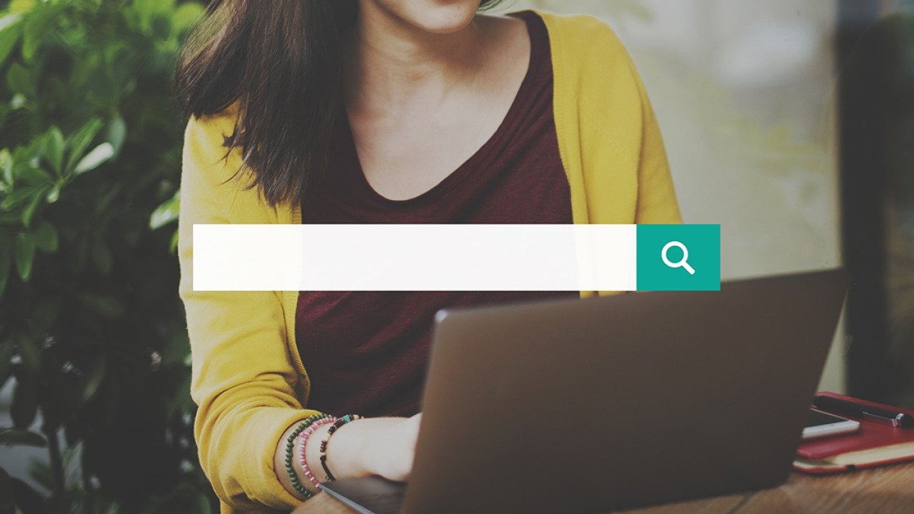 A search bar over a background of a woman using a laptop.
