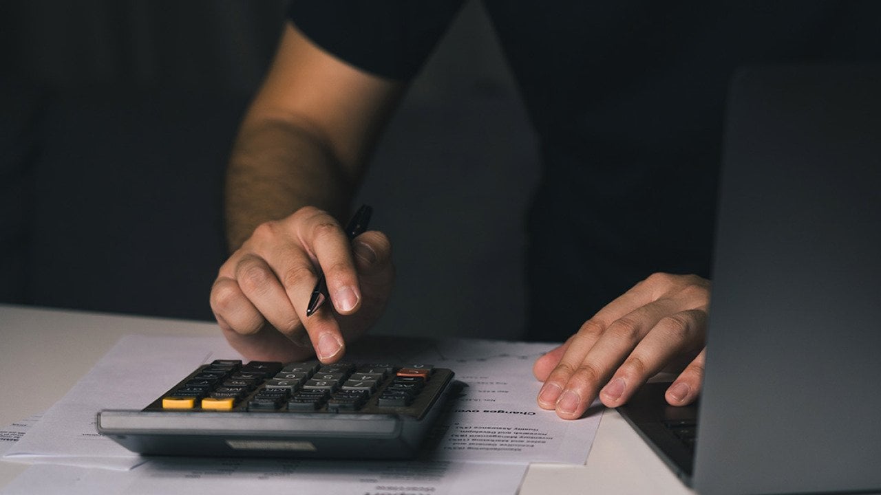 A man uses a calculator to compute monthly expenses.