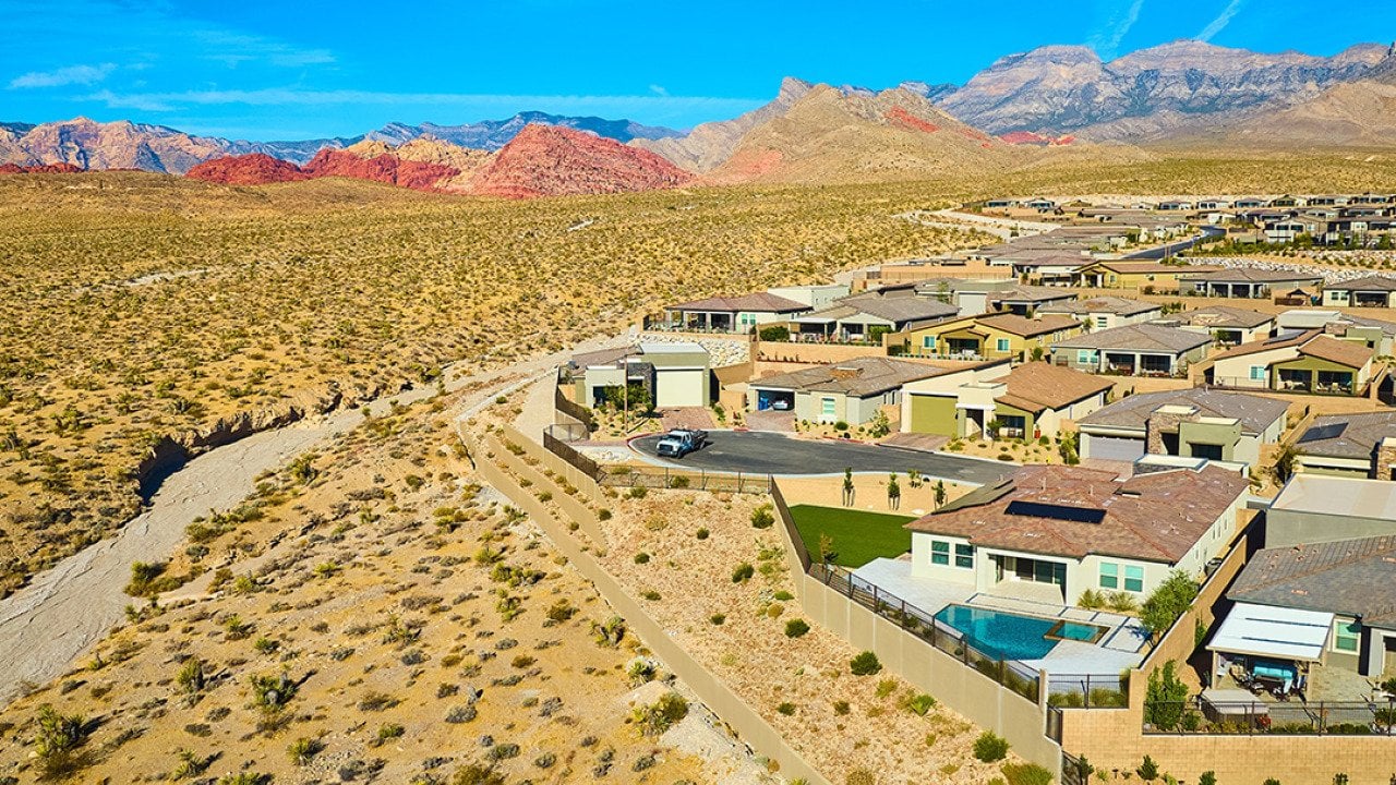 An aerial view of a modern suburban residential neighborhood situated in a mountainous desert area.