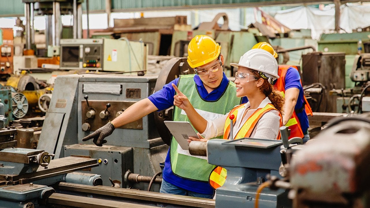 Heavy industry machine workers coordinating on site.