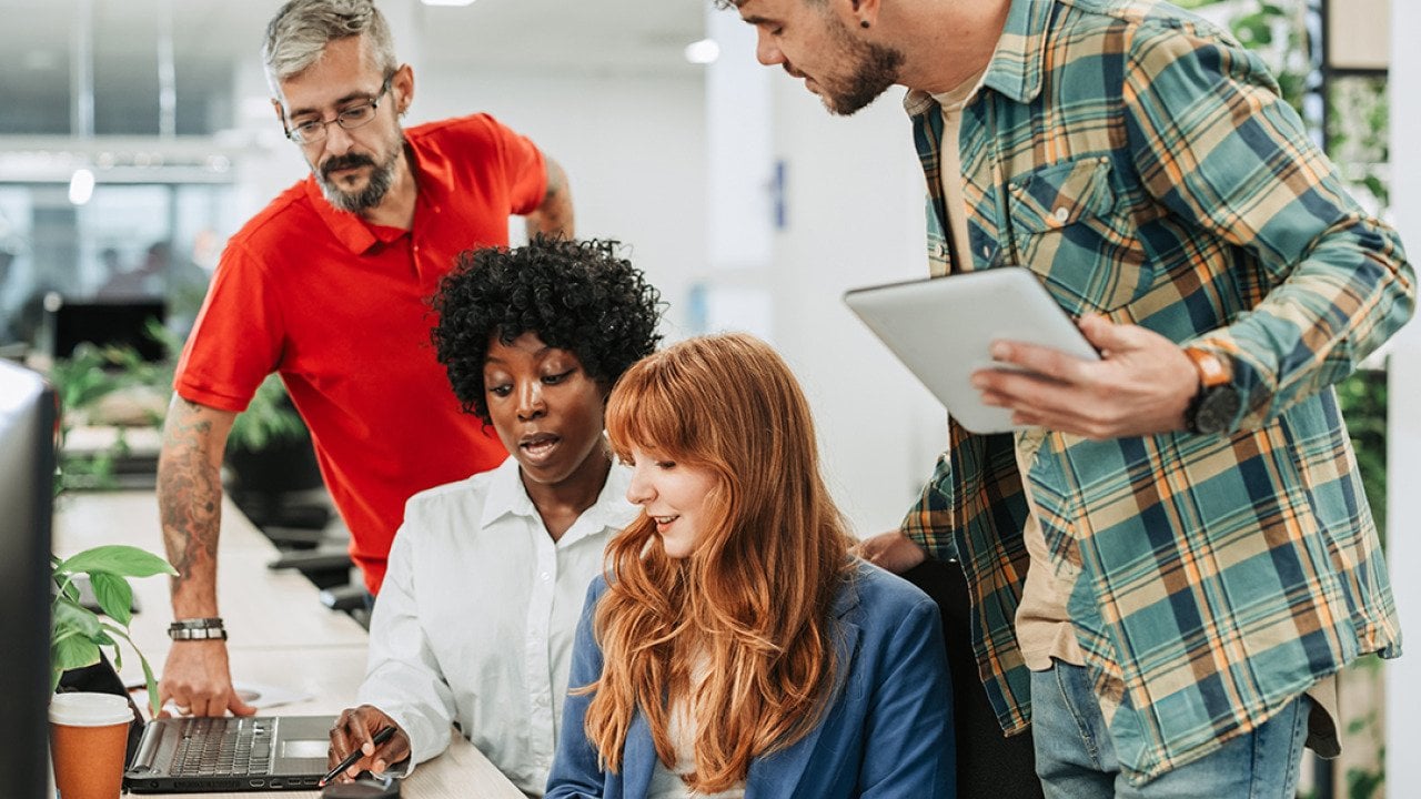 A diverse four-member team sharing ideas in an office.