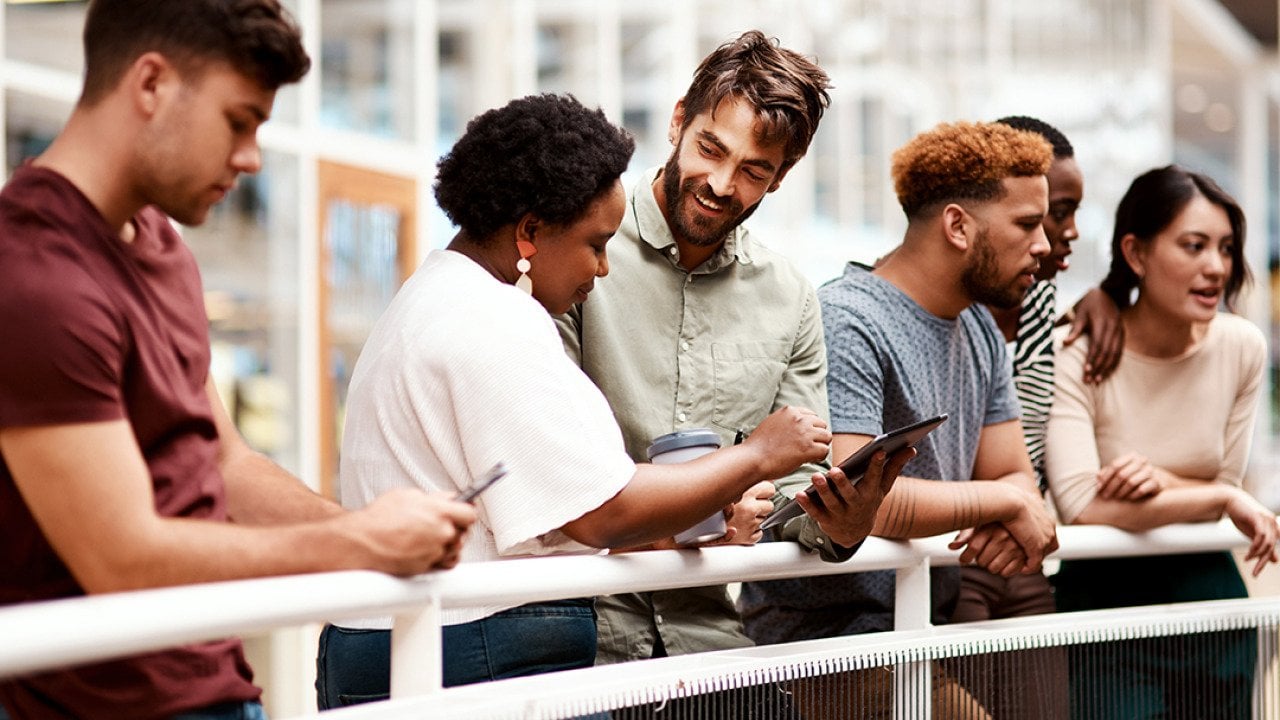 An office team engaged in discussion while standing by a railing.