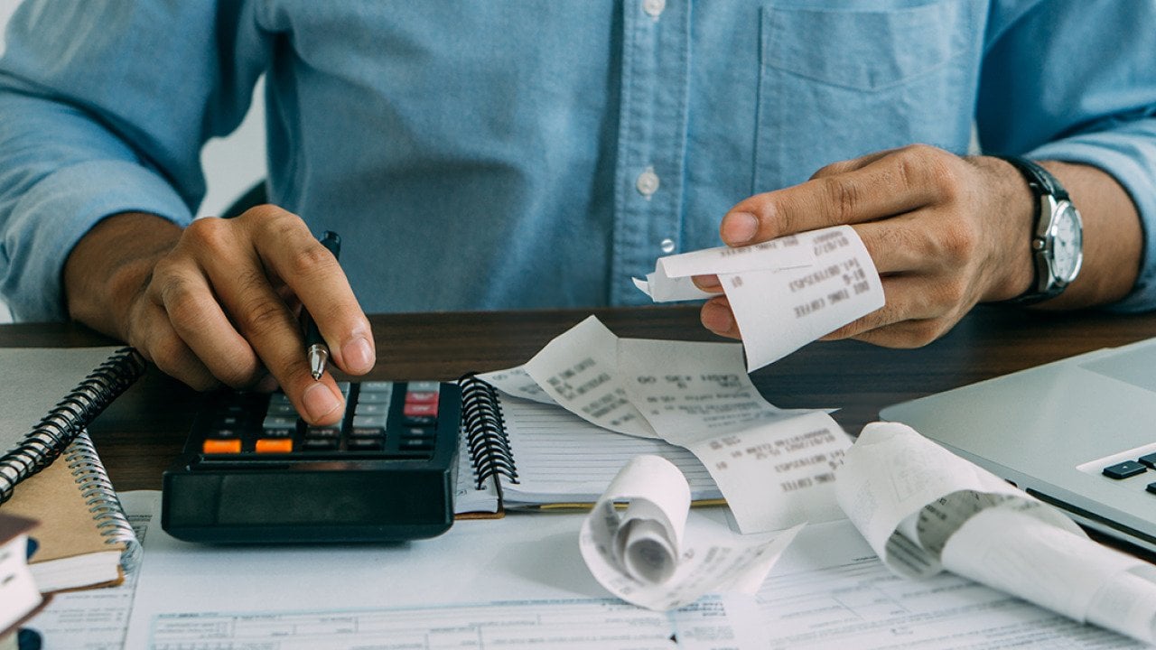 A man computes bills using a calculator.