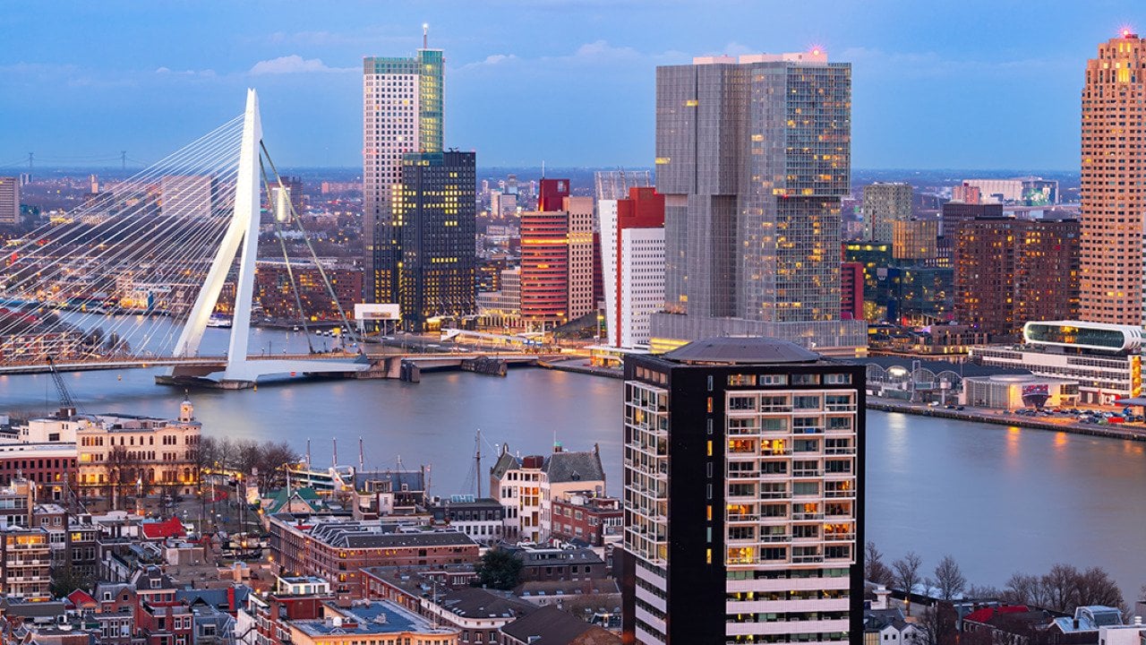 View of the Rotterdam city skyline over the Nieuwe Maas River during twilight in Netherlands.
