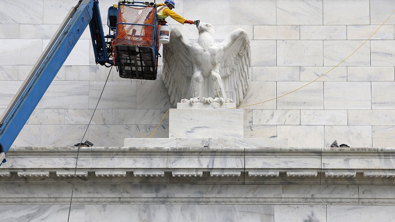 Workers paint an eagle statue on the Marriner S. Eccles Federal Reserve Board Building in Washington, DC.