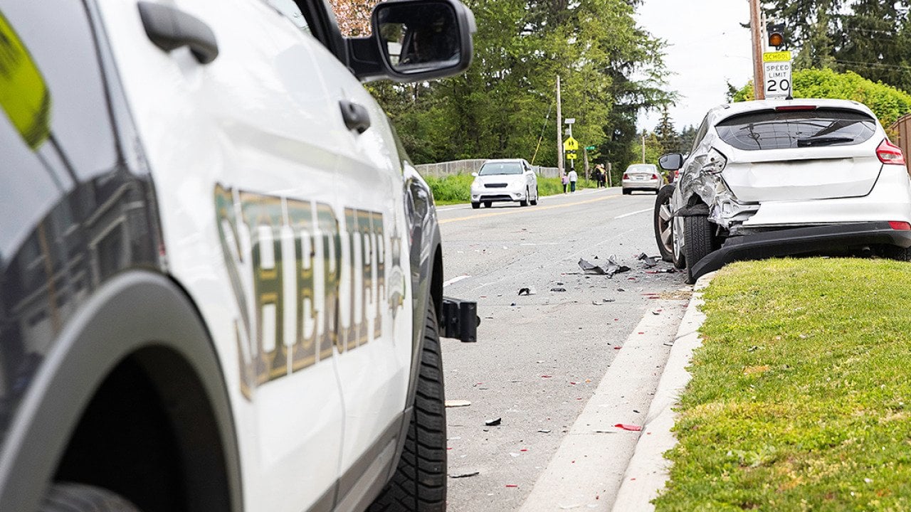 A car crash on the side of a street from the point of view of a sheriff's car.