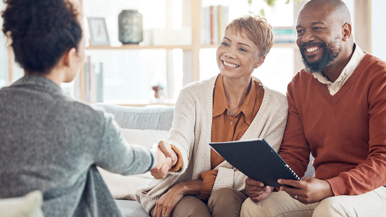 A couple shaking hands with a financial advisor.