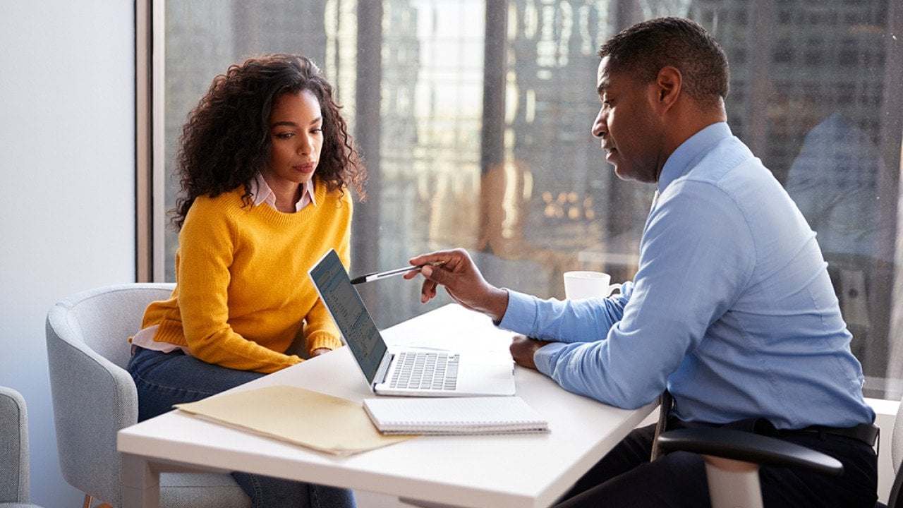 A young woman engaged in a discussion with a financial advisor in an office.