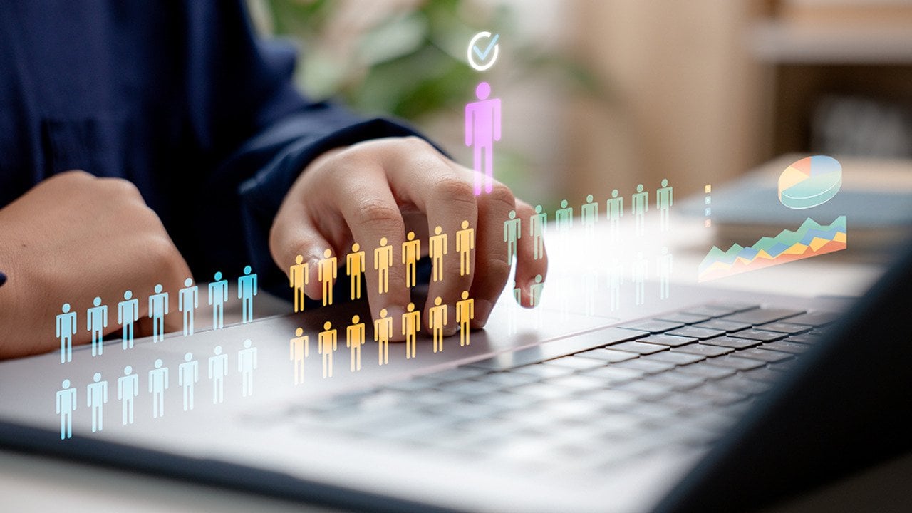 Concept of HR recruitment showing digital human figures illustrated over a businessperson using a laptop.