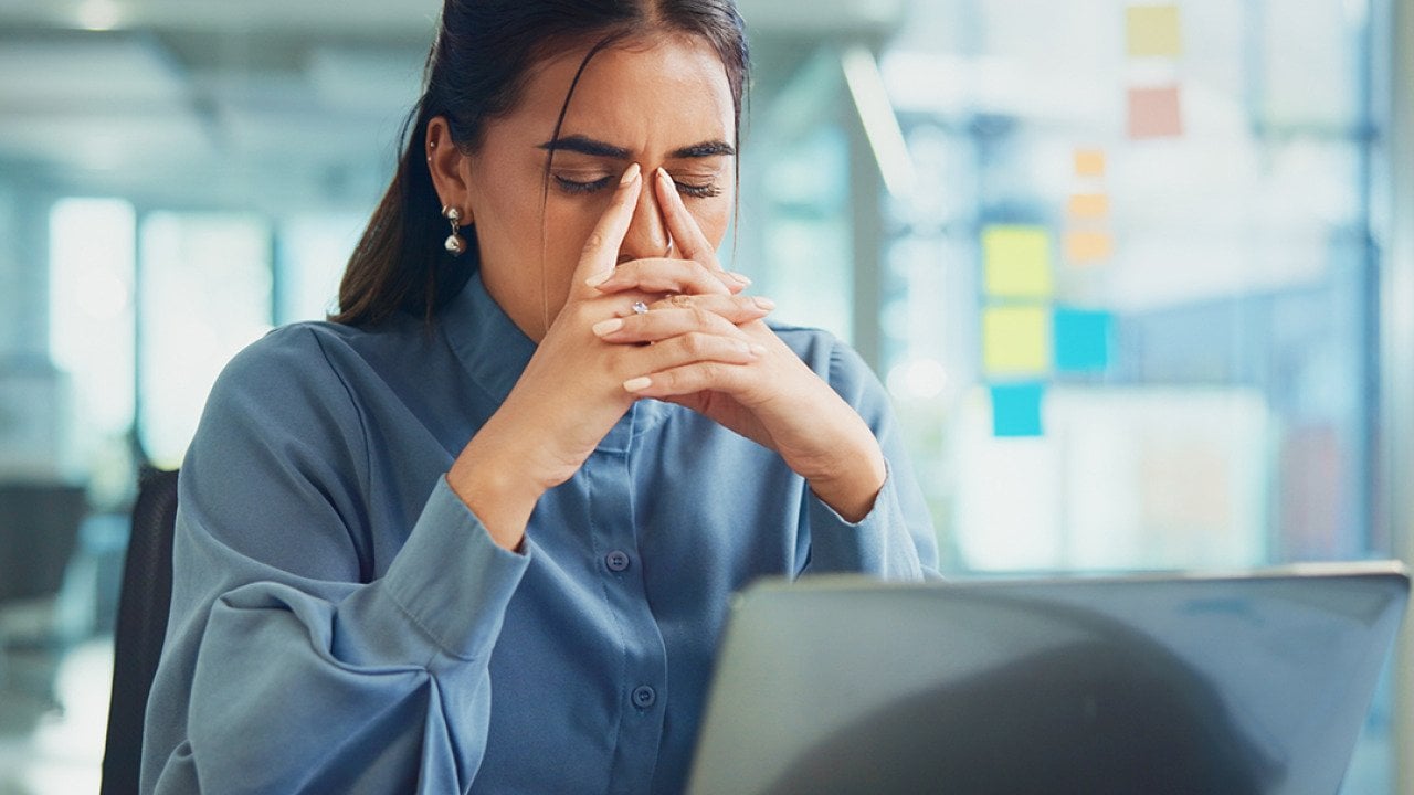 A frustrated young woman in front of her laptop at work.
