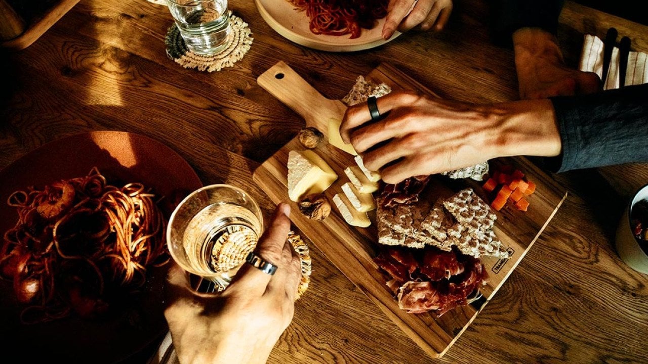 Top view of ptwo people having a Thanksgiving charcuterie board and drinks. They are wearing Oura rings.
