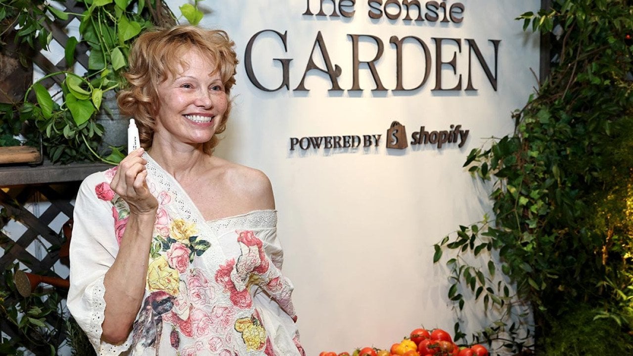 Pamela Anderson poses holding up a lip produce in front of