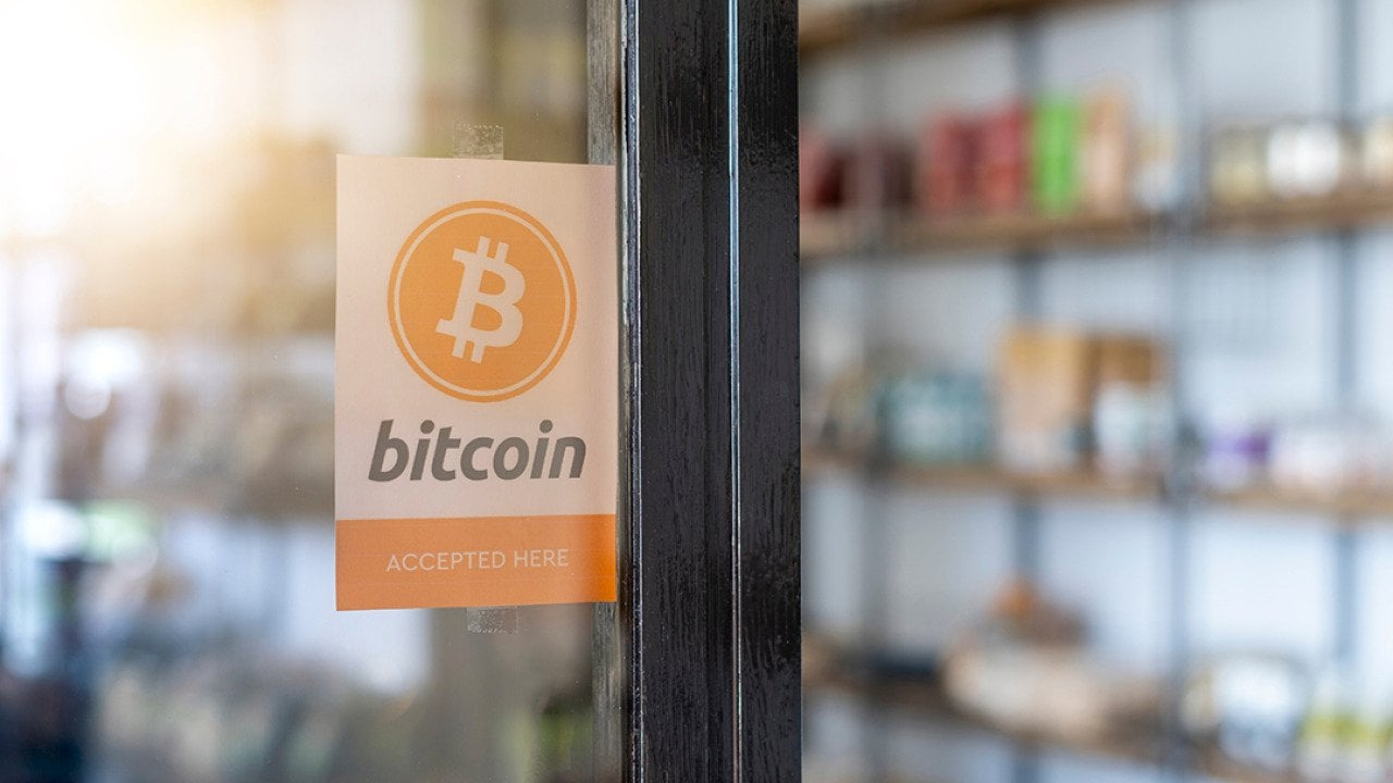A entrance door sign showing 'Bitcoin (is) accepted here)'.