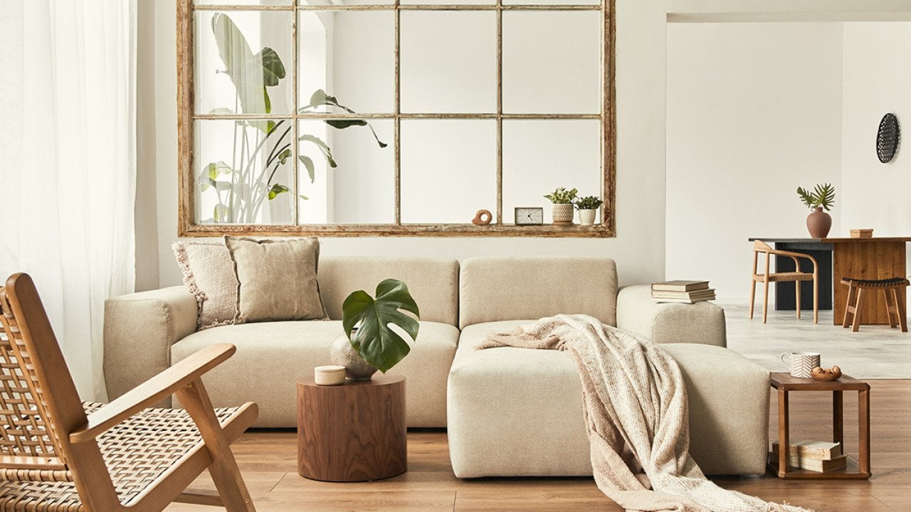 Interior of a modern living room with a modular sofa, decorated with beige and wooden motifs.