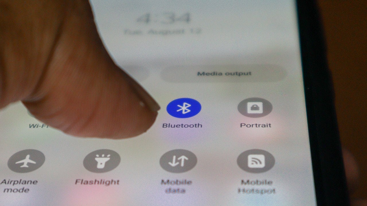 Close up view on a person's finger tapping on the bluetooth app on a phone.
