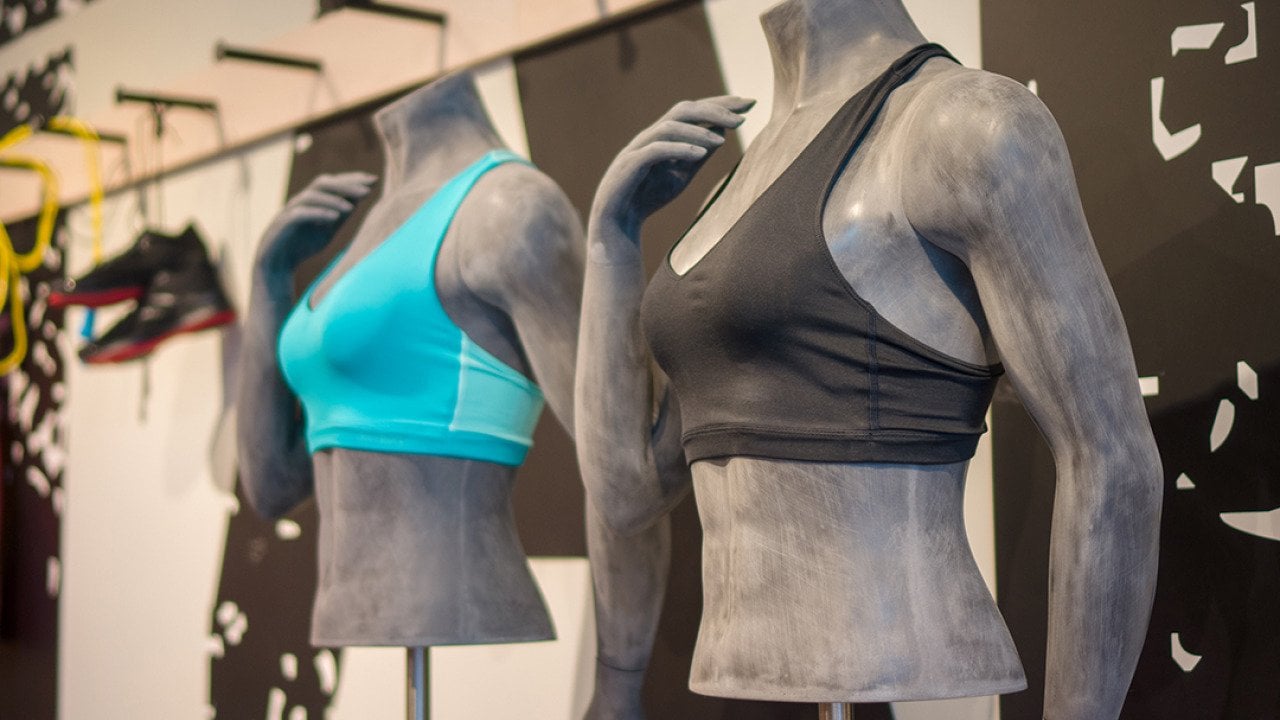Different colors of women's sports bra displayed on torso mannequins at a sports clothing store.