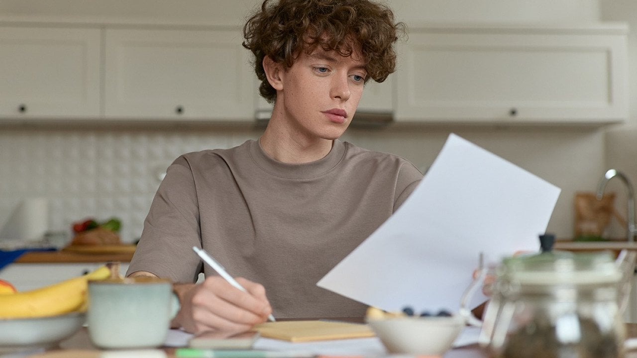 A young man reviewing a document during breakfast.