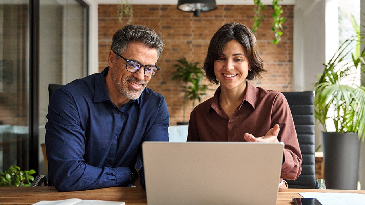 Two business executive leaders happily engaged in a discussion in an office.