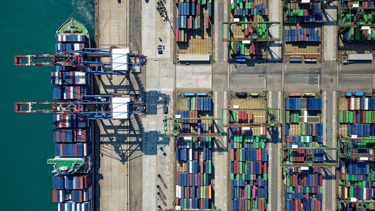 Aerial view on ships, cranes, and cargo containers by the quayside of a dock.