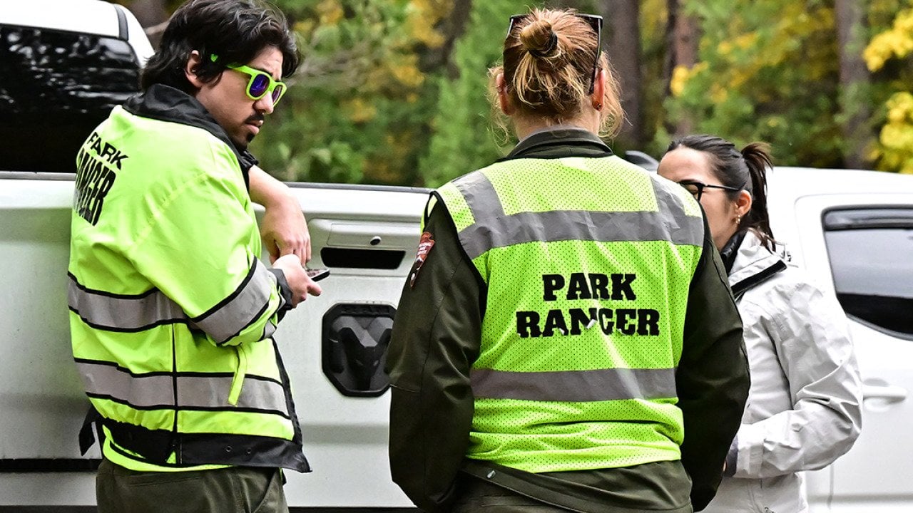 Three park rangers behind their car on duty at Curry Village in the Yosemite Valley at Yosemite National Park, California.