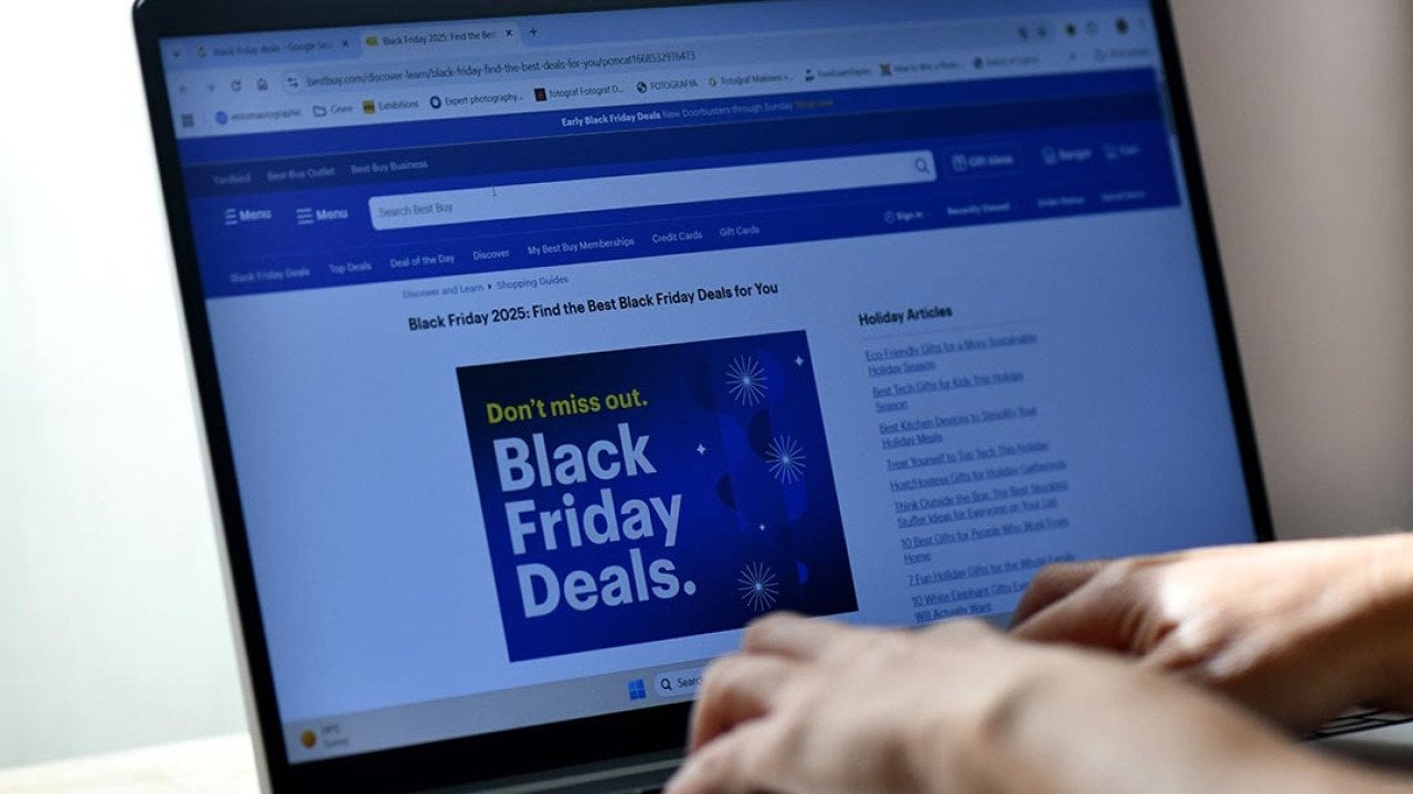 Hands typing on a laptop displaying a Black Friday Deals advertisement page.