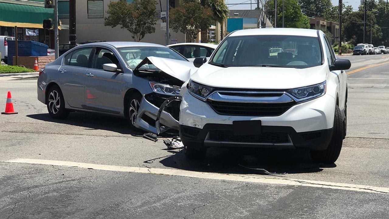 Two modern vehicles involved in a traffic accident are shown stopped in an intersection during the day in Los Angeles.