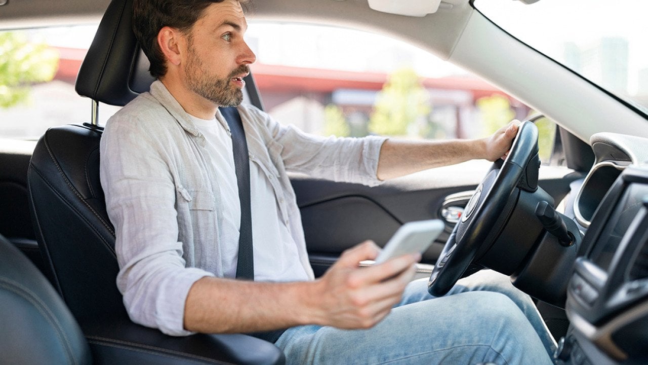 A male driver in shock as he is texting while driving.