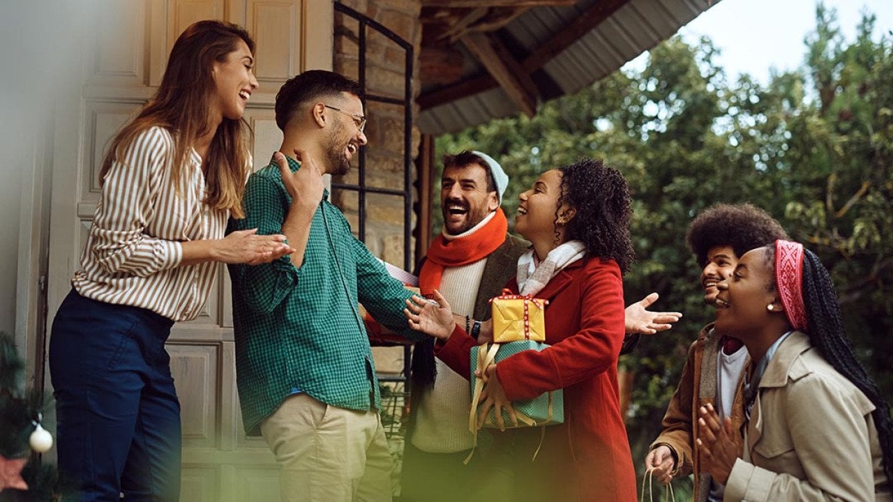 Young happy people greeting with a couple while arriving at their dinner party during winter holidays. 