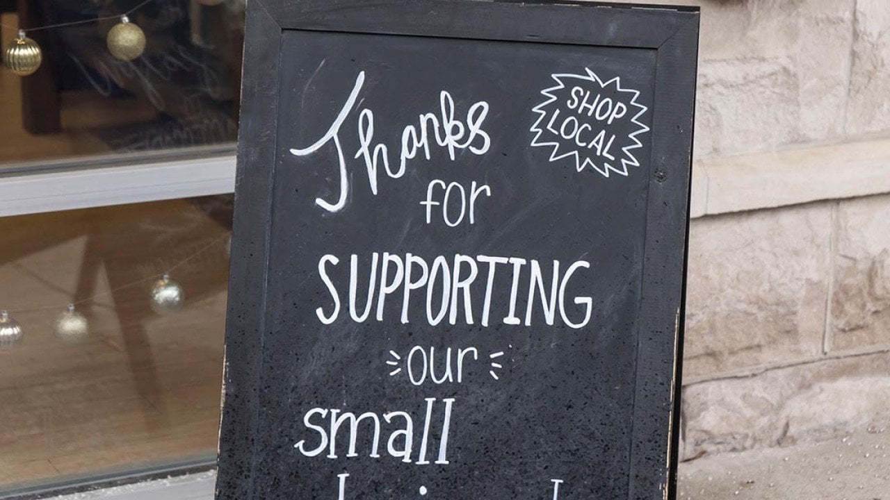 Small business chalkboard sign on sidewalk saying
