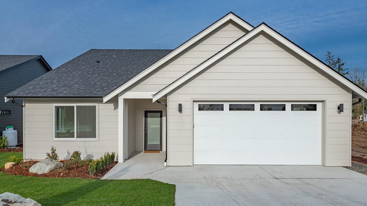 Middle class home exterior small rambler style house with simple style brand new construction blue sky green grass winter season family residence in a suburban neighborhood.