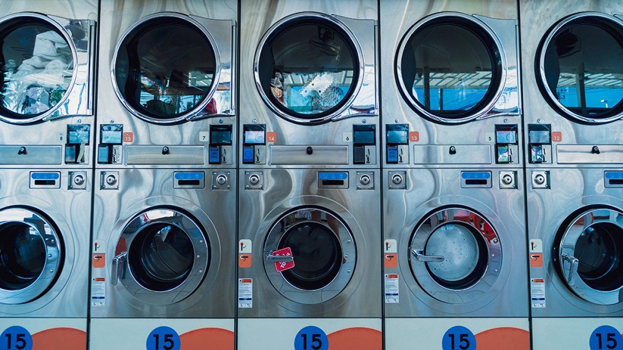 Rows of large industrial laundry machines in a laundromat.