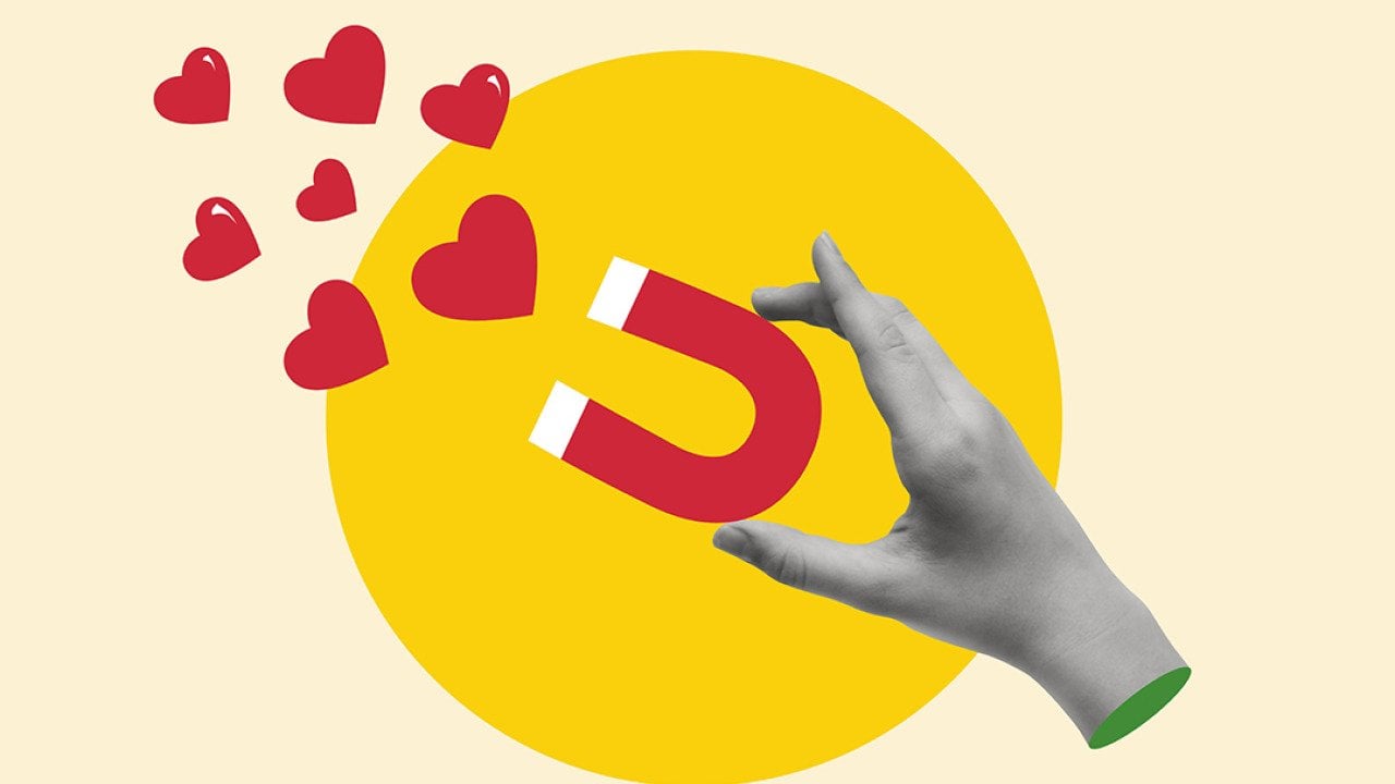 A custom illustration of a hand holding a magnet pulling hearts.