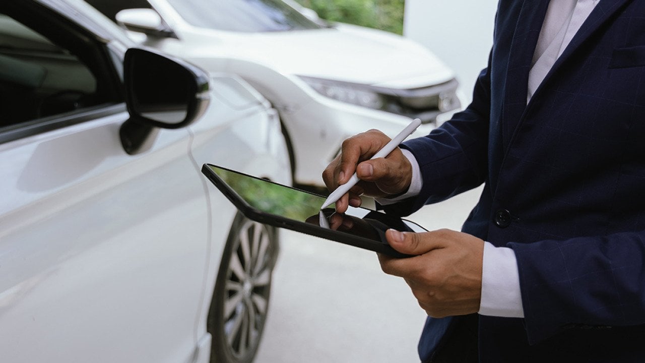 A car insurance agent inspects a damaged vehicle.