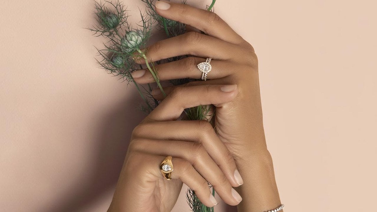 Hands of a bride holding flowers and showcasing diamond cut rings.