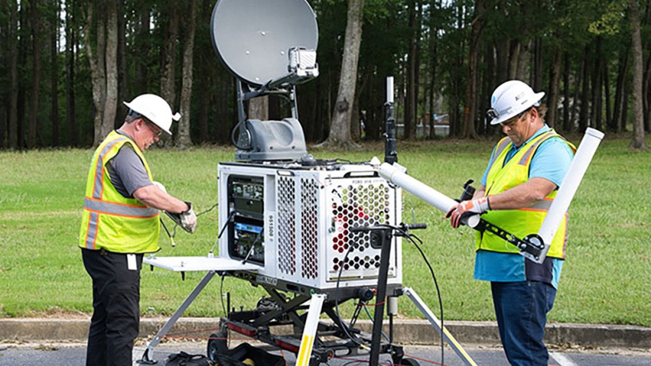 A technical staff setting up a portable satellite asset.