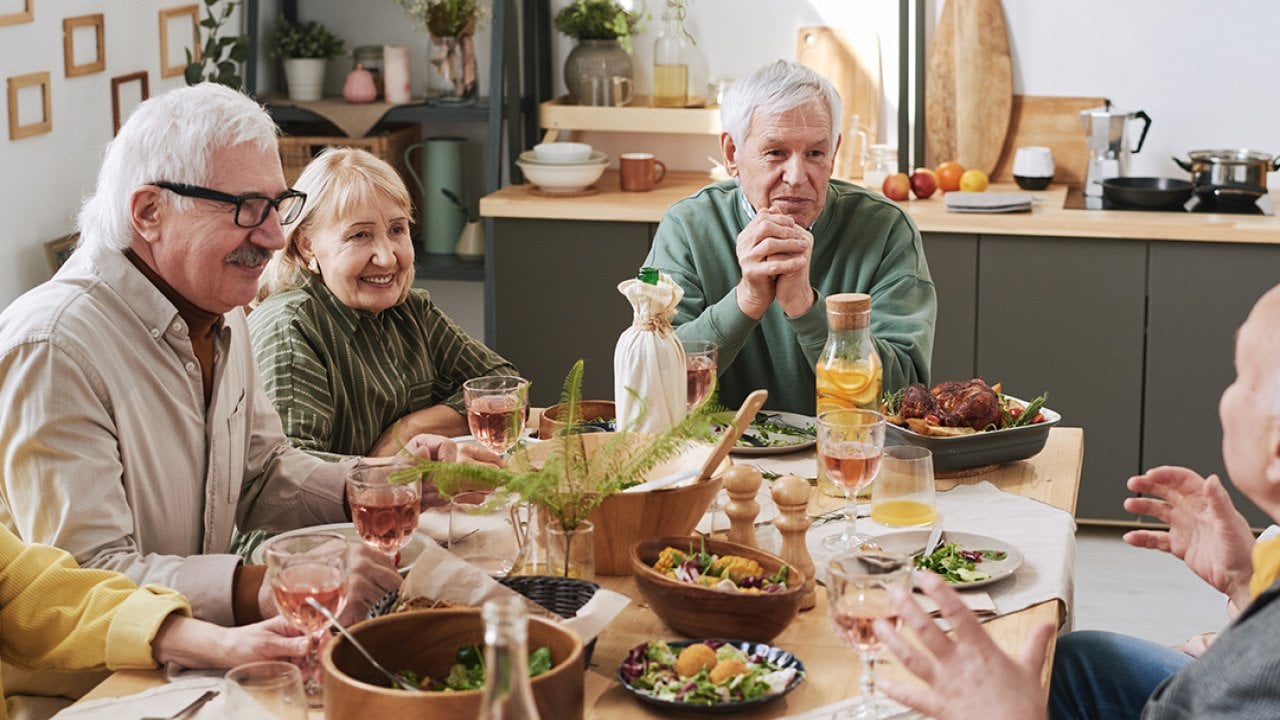 A group of senior people talking to each other at the dinner table.