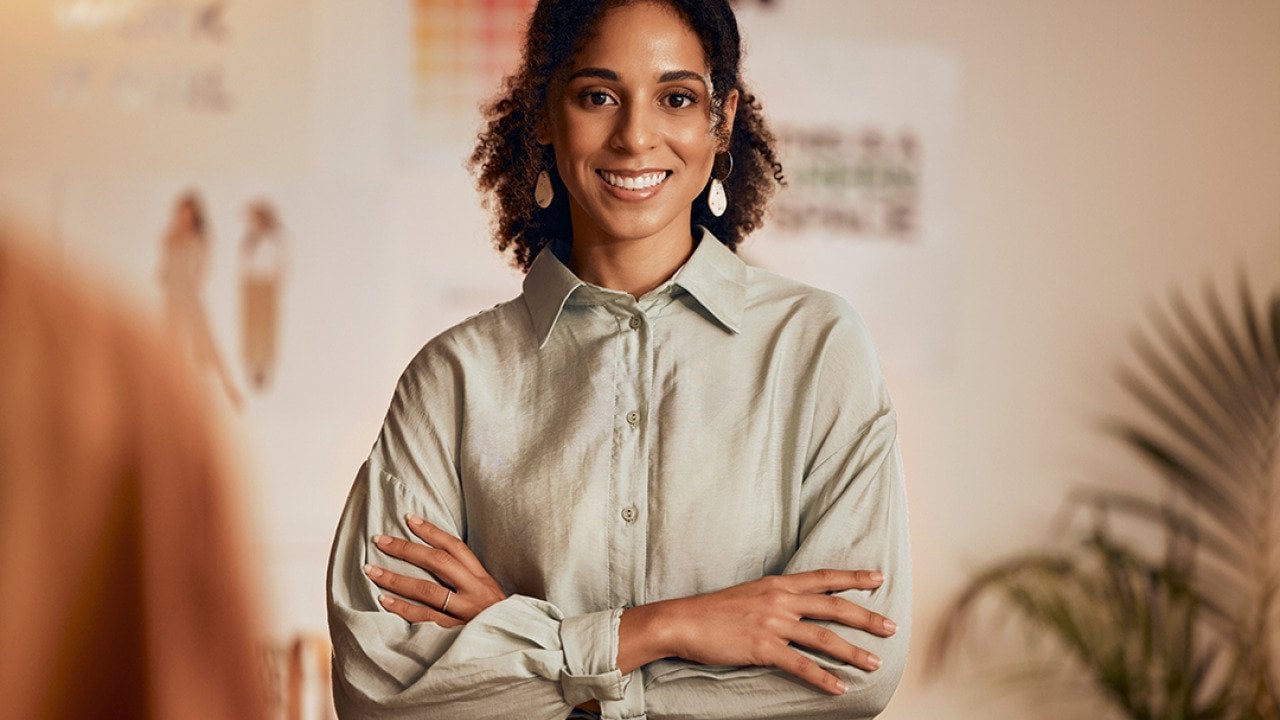 A black female fashion designer posing in her studio.