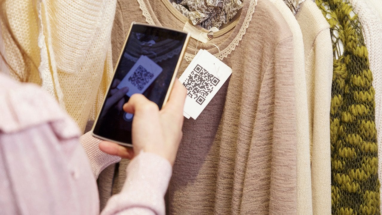 A woman scanning a clothing item's QR code on her phone.