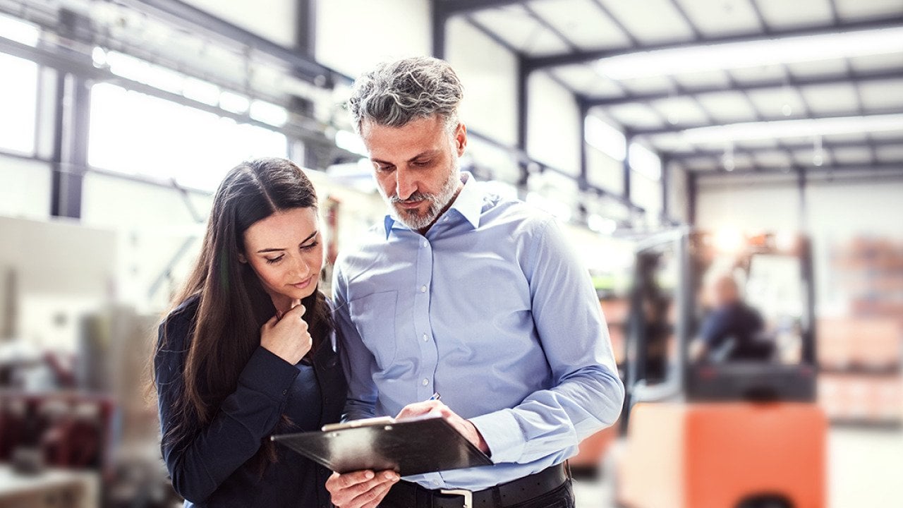 Warehouse manager and employee planning transport process in warehouse.