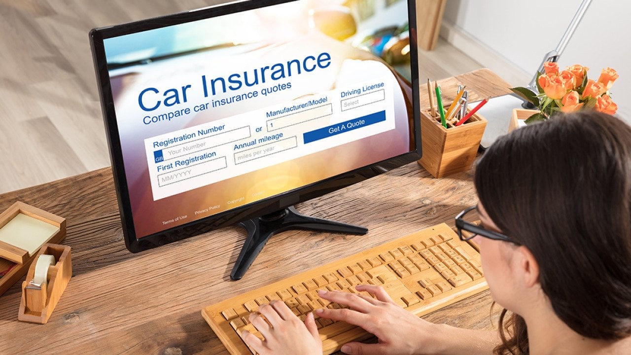 A businesswoman filling out a car insurance form using a desktop.