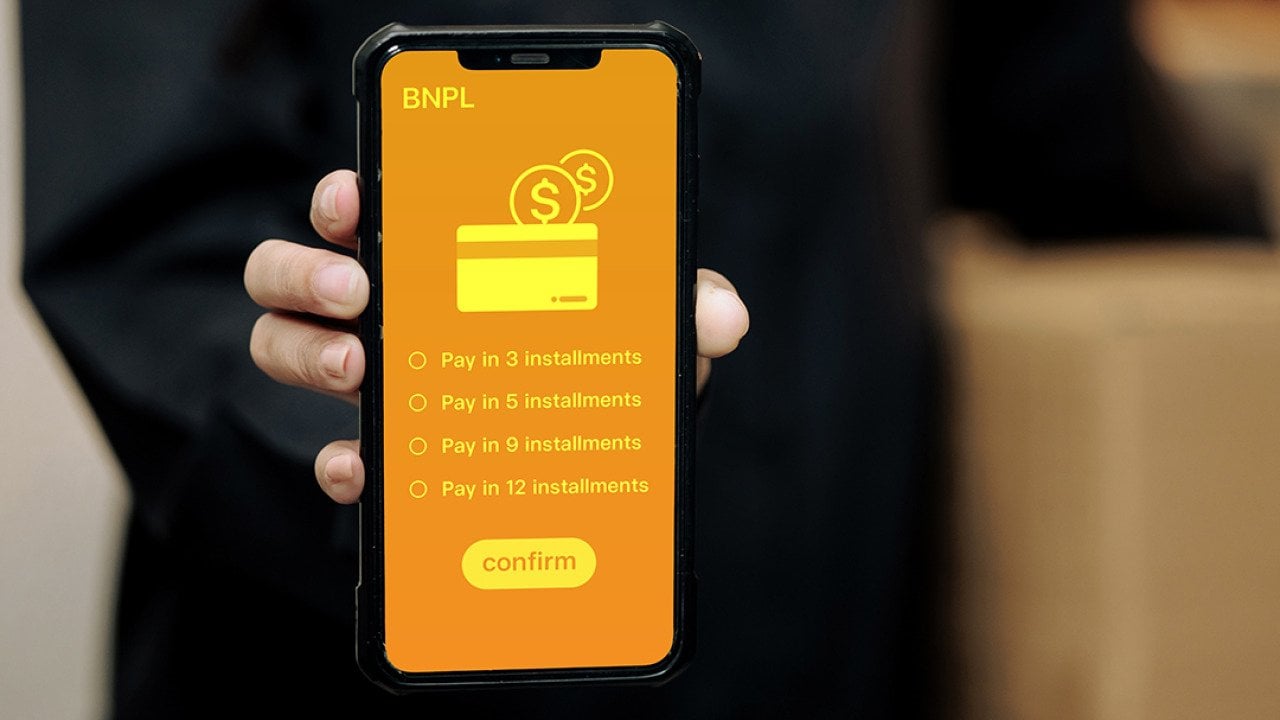 A person holding a smartphone displaying installment options for Buy Now, Pay Later method.