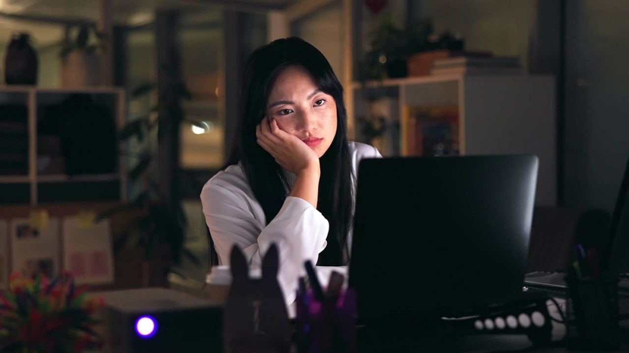 A tired female employee working overtime in the office at night.