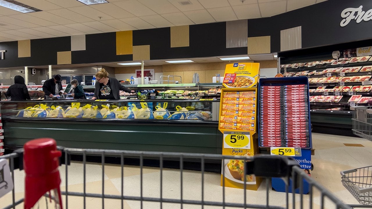 Wide view of people shopping for Butterball Thanksgiving turkeys inside a grocery store.