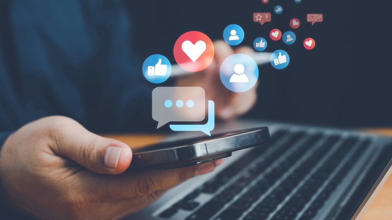 Social media interaction graphics illustrated over a person using a smartphone and laptop.