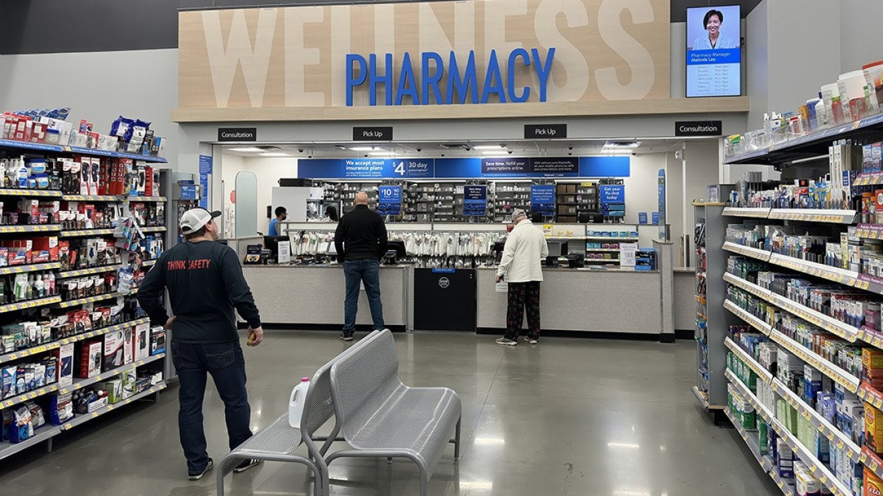 Customers picking up items at a pharmacy counter.