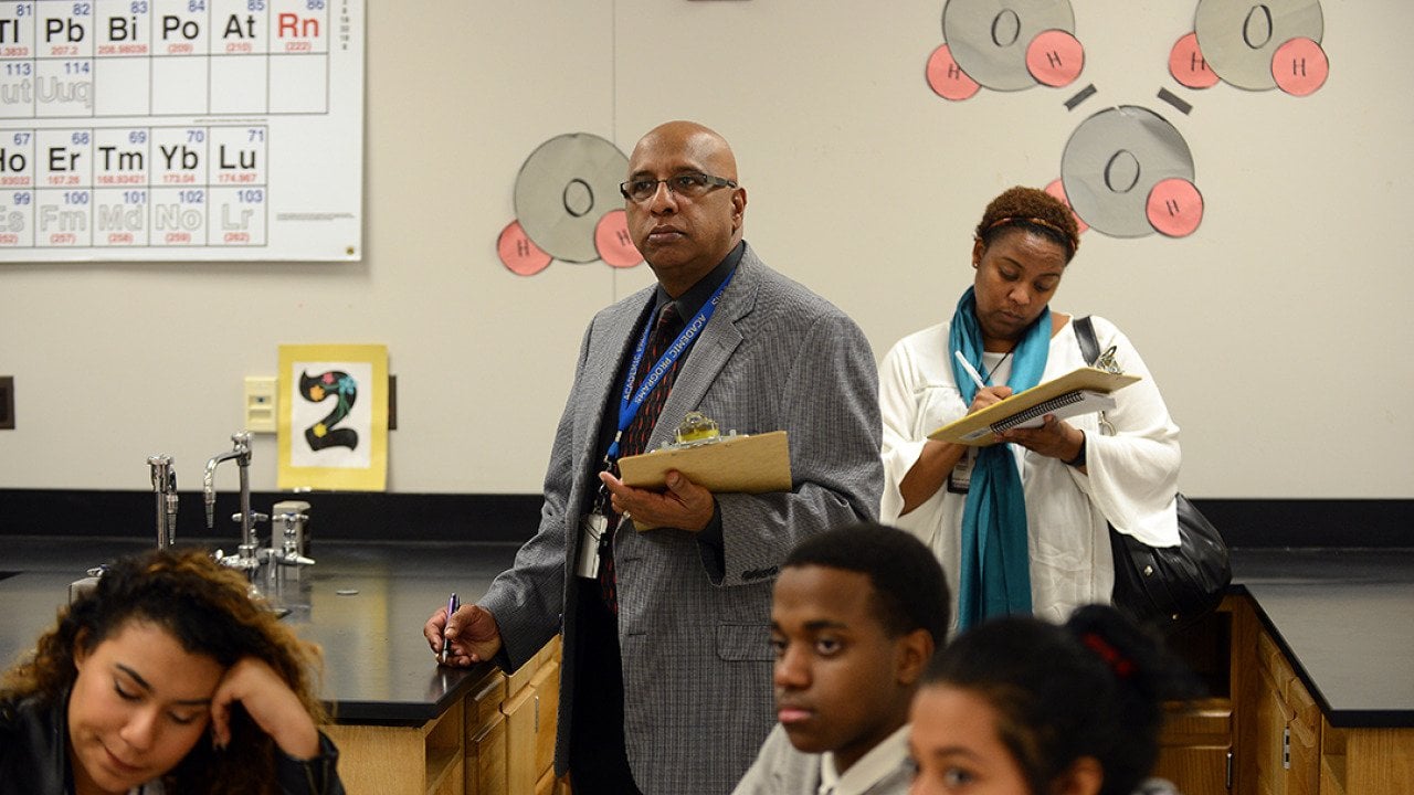 Godfrey Rangasammy, Supervisor of Science, background center, and Tanisha Johnson, a Science Coach, right, background, observe a chemistry class as Literacy coaches at Northwestern High School in Hyattsville, Maryland.