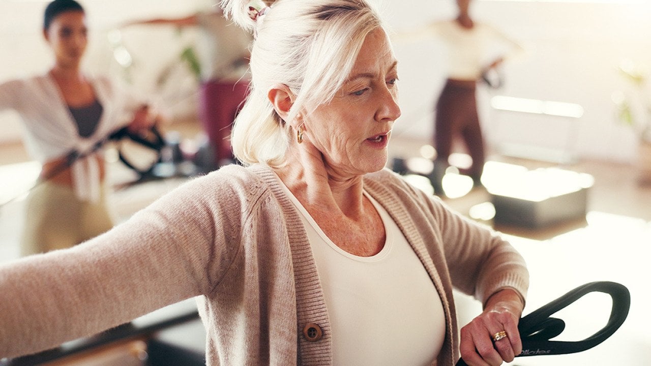 A mature female fitness coach leading a pilates class.